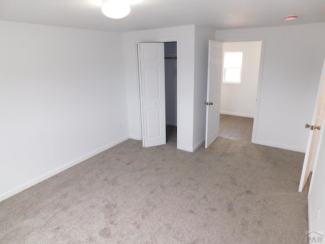 unfurnished bedroom with light carpet, baseboards, and a closet