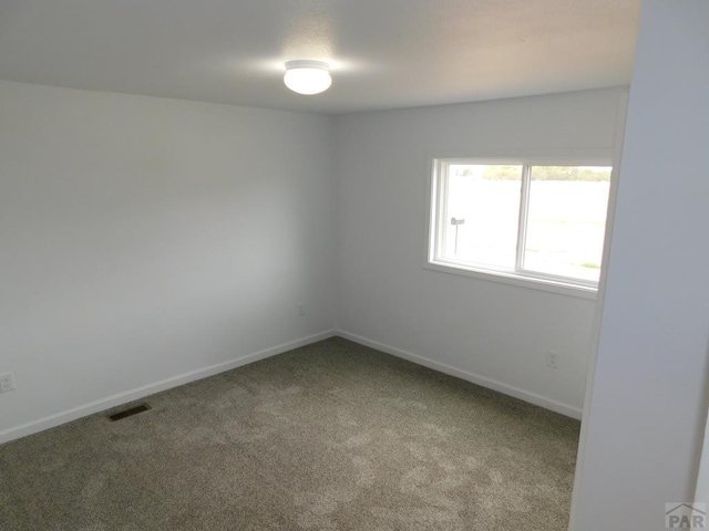 empty room with carpet, visible vents, and baseboards