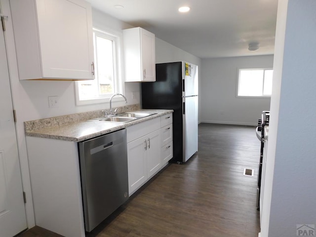 kitchen with white cabinets, stainless steel appliances, a sink, and light countertops