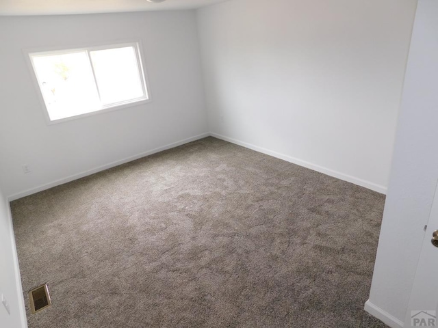 unfurnished room featuring visible vents, dark carpet, and baseboards