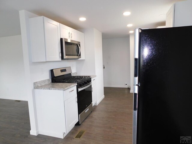 kitchen featuring dark wood finished floors, stainless steel appliances, light countertops, visible vents, and white cabinetry