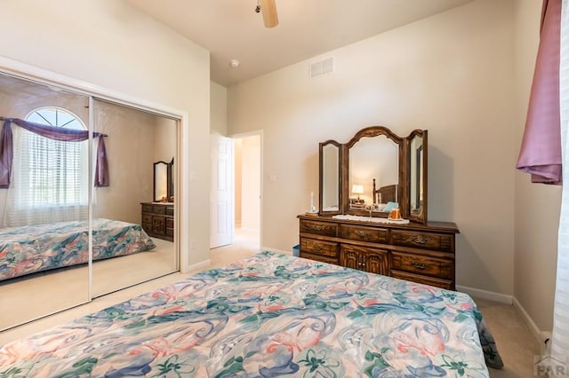 bedroom featuring ceiling fan, light colored carpet, visible vents, baseboards, and a closet