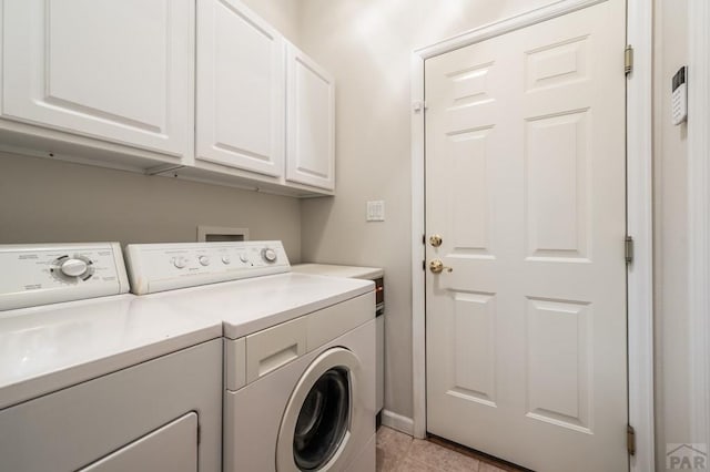 laundry area featuring washing machine and dryer, cabinet space, and light tile patterned floors