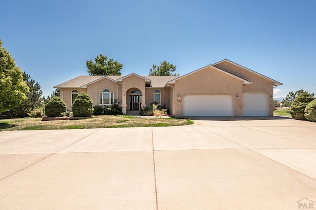 view of front of home featuring a garage, concrete driveway, and stucco siding