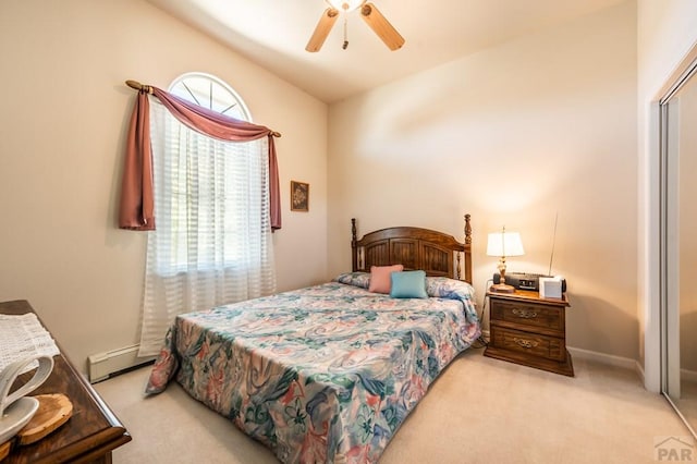 bedroom with a baseboard radiator, a closet, light colored carpet, ceiling fan, and baseboards