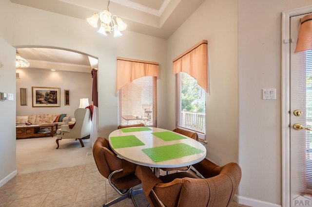 dining room with arched walkways, a notable chandelier, a raised ceiling, light tile patterned flooring, and light carpet