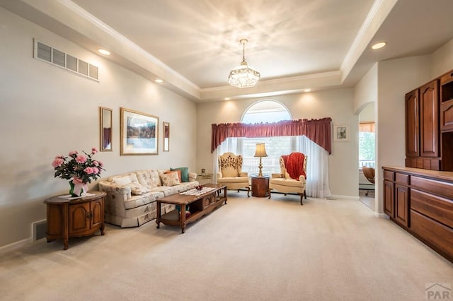 living area with visible vents, ornamental molding, a wealth of natural light, and light colored carpet