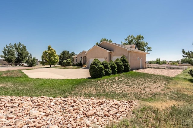 view of side of home with a garage, a yard, driveway, and stucco siding