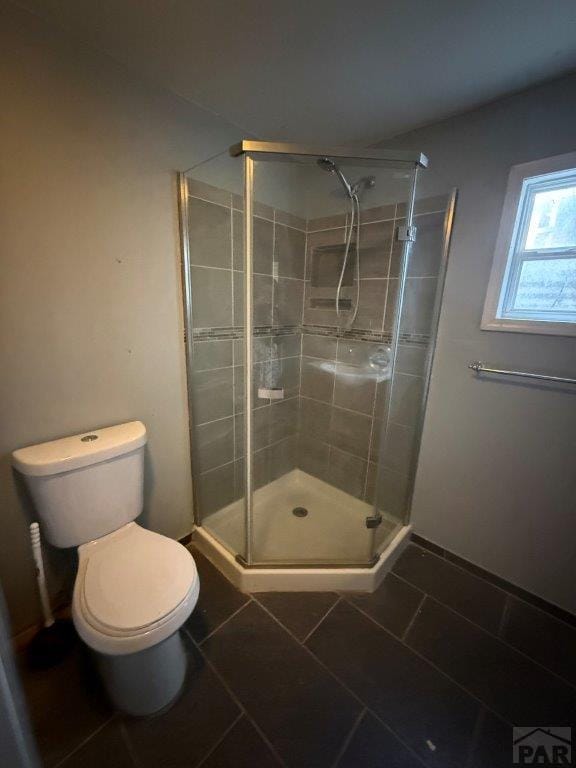 full bathroom with a stall shower, tile patterned flooring, and toilet