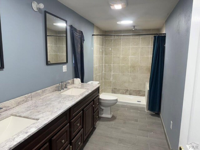 full bathroom featuring double vanity, a stall shower, and a sink
