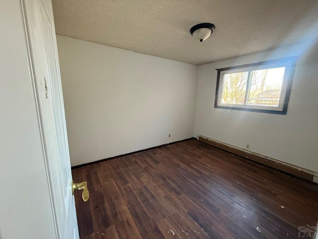 empty room featuring dark wood-style floors and a textured ceiling