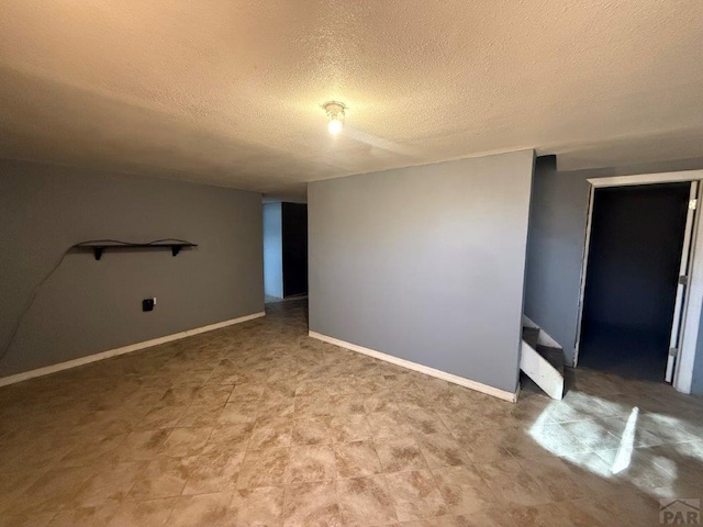 spare room with stairway, baseboards, and a textured ceiling