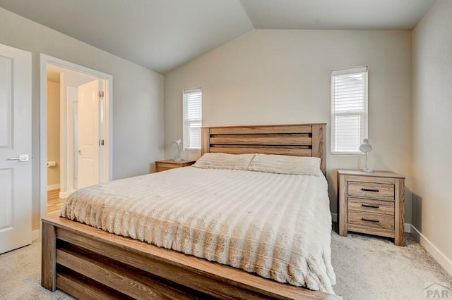 bedroom with baseboards, vaulted ceiling, and light colored carpet