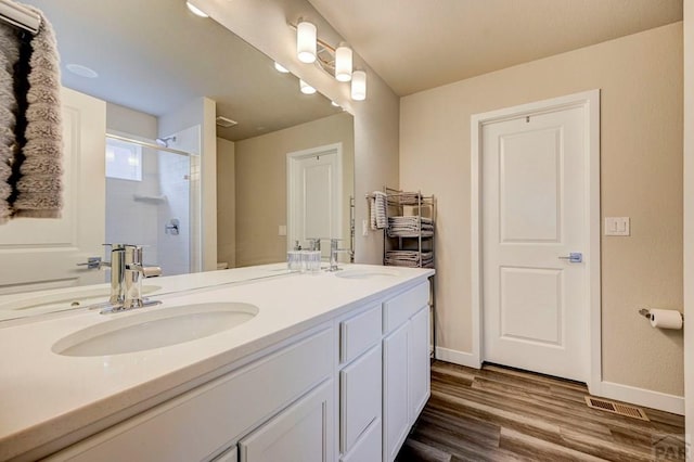 full bathroom featuring wood finished floors, a stall shower, a sink, and visible vents