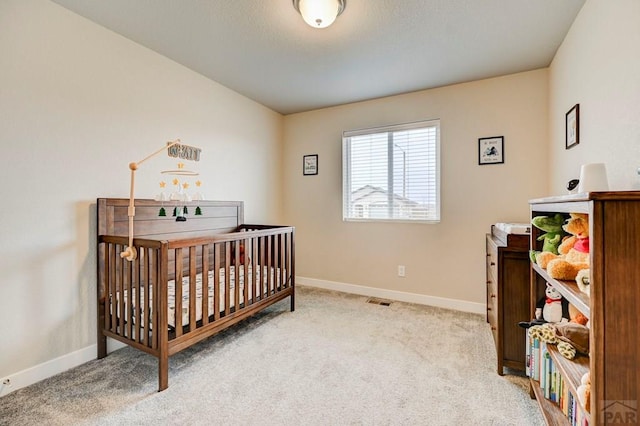 bedroom with carpet floors, visible vents, baseboards, and a crib