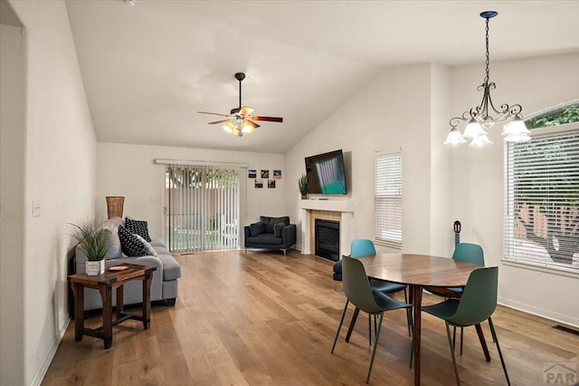 4315 Outlook Blvd Unit L, Pueblo, CO 81008 - dining space featuring lofted ceiling, a tiled fireplace, wood finished floors, a ceiling fan, and baseboards