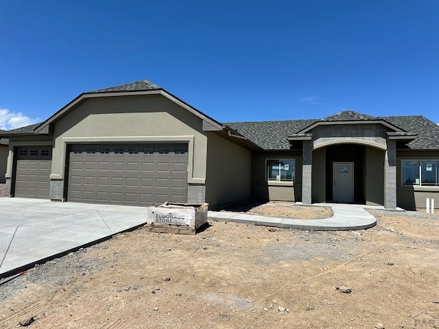 5400 Darter Ct, Pueblo, CO 81008 - view of front of house featuring a garage, stucco siding, driveway, and roof with shingles