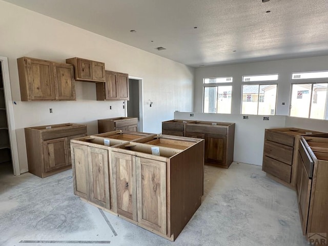 5400 Darter Ct, Pueblo, CO 81008 - kitchen with a kitchen island, unfinished concrete flooring, and brown cabinets