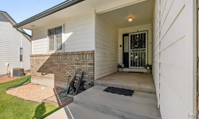 property entrance featuring cooling unit and brick siding