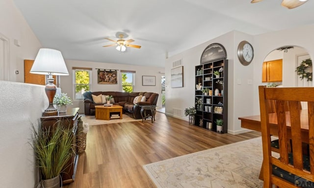 living room with light wood finished floors, visible vents, and a ceiling fan