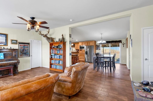 living room featuring baseboards, dark wood-type flooring, and ceiling fan with notable chandelier