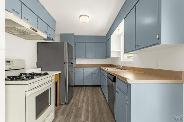 kitchen with white gas stove, blue cabinets, under cabinet range hood, and wood finished floors