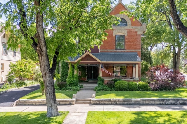 326 W Pitkin Ave, Pueblo, CO 81004 - view of front facade featuring brick siding, a front yard, and a porch