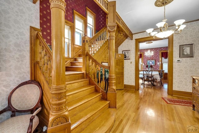 326 W Pitkin Ave, Pueblo, CO 81004 - stairs featuring a chandelier, wallpapered walls, wood finished floors, ornamental molding, and baseboards