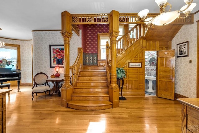 326 W Pitkin Ave, Pueblo, CO 81004 - staircase with wallpapered walls, a chandelier, wood finished floors, and crown molding