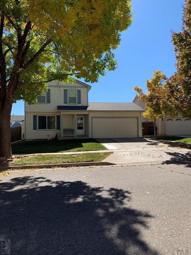 traditional-style house with a front lawn, concrete driveway, fence, and an attached garage