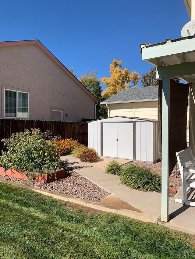 view of yard with fence, an outdoor structure, and a storage unit