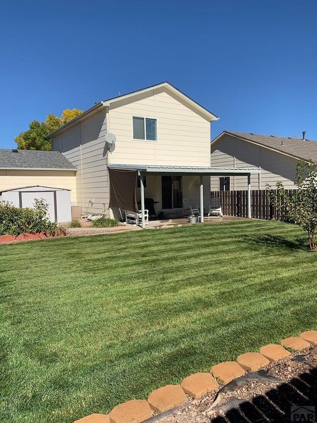 rear view of house featuring a patio, a lawn, and fence