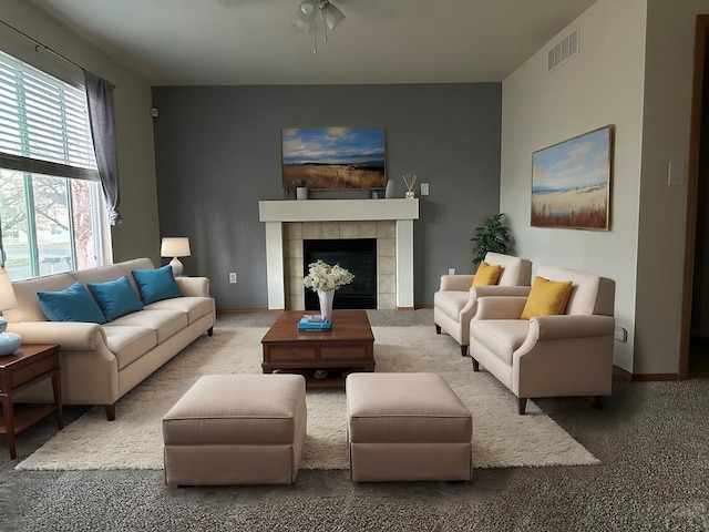 carpeted living area featuring a fireplace, visible vents, and baseboards