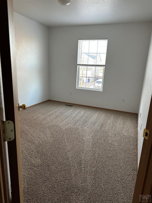 unfurnished room featuring carpet, a textured ceiling, and baseboards