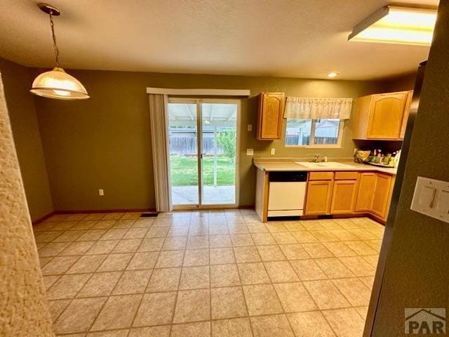 kitchen featuring baseboards, light countertops, dishwasher, and pendant lighting