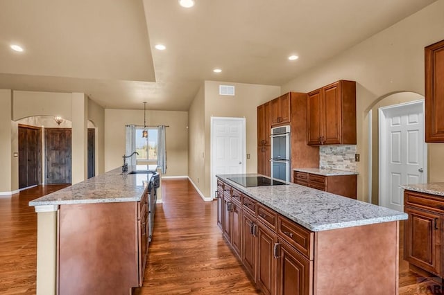 368 S Camino De Los Ranchos, Pueblo West, CO 81007 - kitchen with a kitchen island with sink, arched walkways, stainless steel double oven, black electric cooktop, and recessed lighting