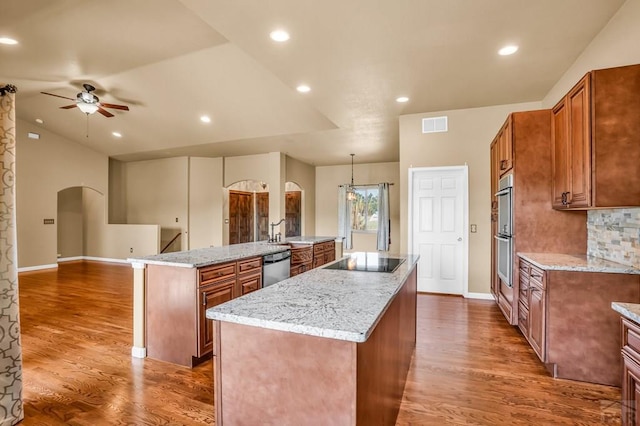 368 S Camino De Los Ranchos, Pueblo West, CO 81007 - kitchen with a spacious island, arched walkways, stainless steel appliances, a ceiling fan, and brown cabinetry