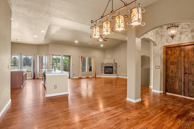 368 S Camino De Los Ranchos, Pueblo West, CO 81007 - unfurnished living room with arched walkways, wood finished floors, a fireplace, recessed lighting, and a textured ceiling