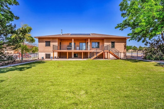 368 S Camino De Los Ranchos, Pueblo West, CO 81007 - back of property featuring stairs, solar panels, stucco siding, and a lawn
