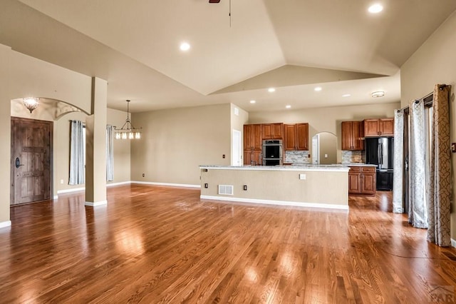368 S Camino De Los Ranchos, Pueblo West, CO 81007 - kitchen with freestanding refrigerator, arched walkways, brown cabinetry, open floor plan, and light countertops