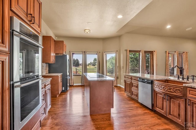 368 S Camino De Los Ranchos, Pueblo West, CO 81007 - kitchen featuring stainless steel appliances, a center island, wood finished floors, brown cabinets, and recessed lighting