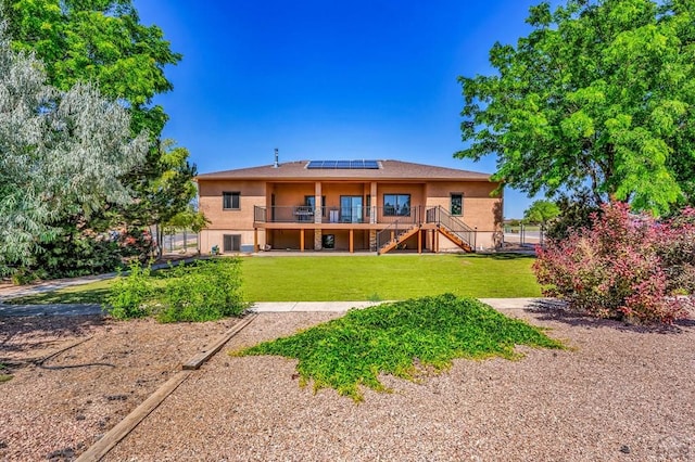 368 S Camino De Los Ranchos, Pueblo West, CO 81007 - rear view of house with stairway, roof mounted solar panels, a yard, and stucco siding