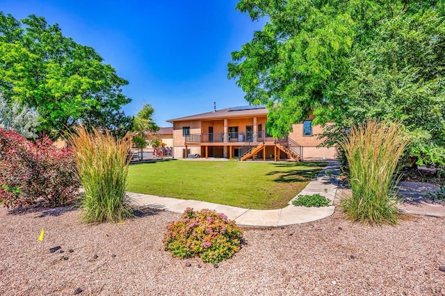 368 S Camino De Los Ranchos, Pueblo West, CO 81007 - rear view of house with stairway, solar panels, a lawn, stucco siding, and a wooden deck