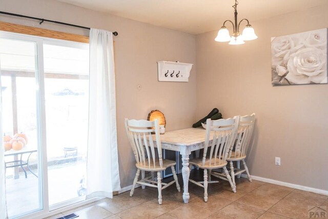 dining space with a chandelier, light tile patterned flooring, and baseboards