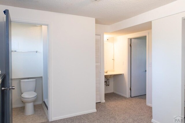 bathroom with a closet, baseboards, a textured ceiling, and toilet