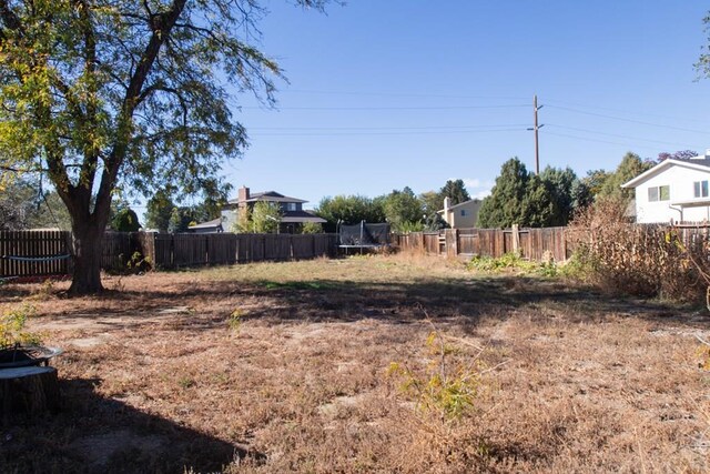 view of yard with a trampoline and fence