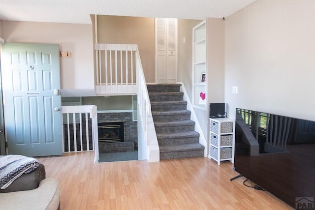 stairway featuring a brick fireplace and wood finished floors