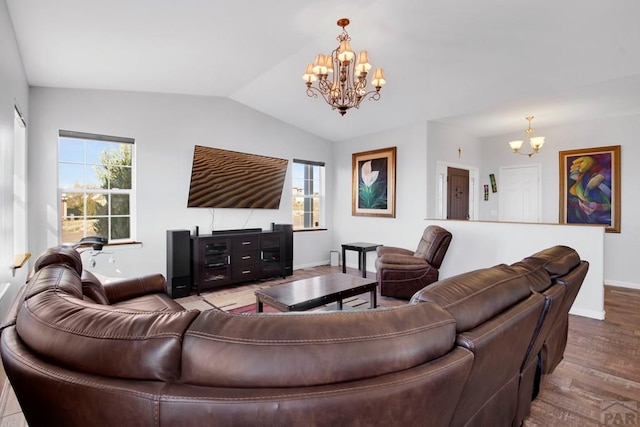 living area featuring vaulted ceiling, baseboards, wood finished floors, and a notable chandelier