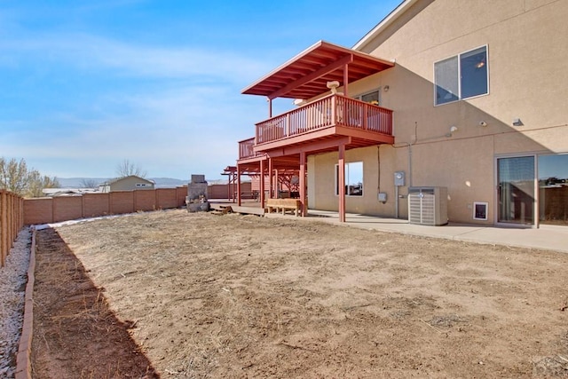 back of property with a fenced backyard, central air condition unit, a wooden deck, stucco siding, and a patio area