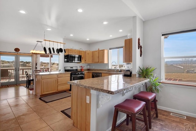 kitchen featuring visible vents, dishwasher, a peninsula, and a kitchen breakfast bar